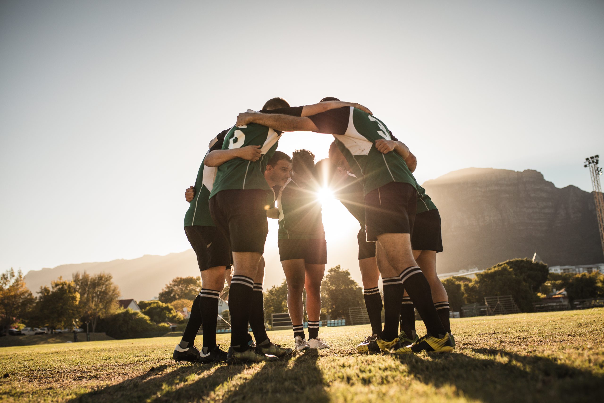 Rugby,Players,Standing,In,A,Circle,With,Their,Hands,On