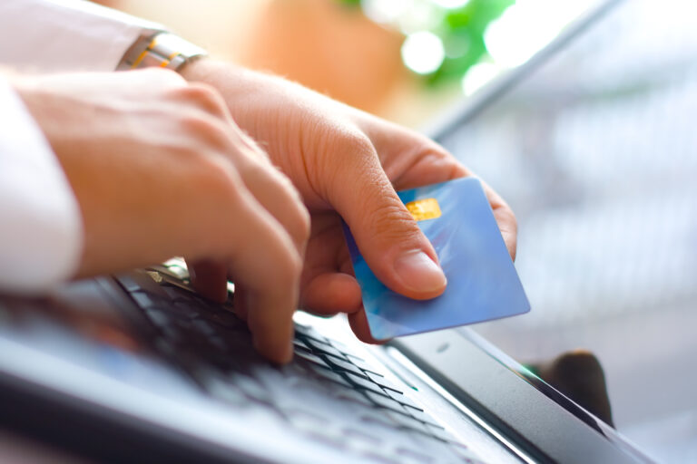 Young,Businessman,Holding,A,Credit,Card,And,Typing.,On-line,Shopping